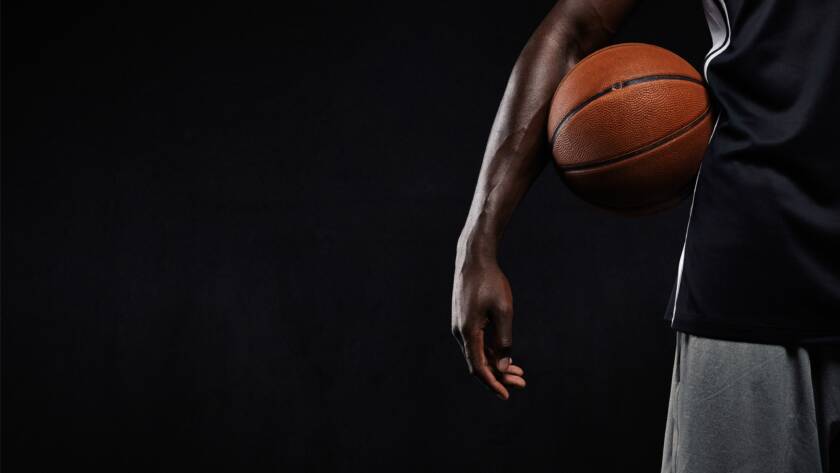 Black basketball player standing with a basket ball