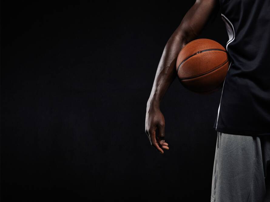 Black basketball player standing with a basket ball